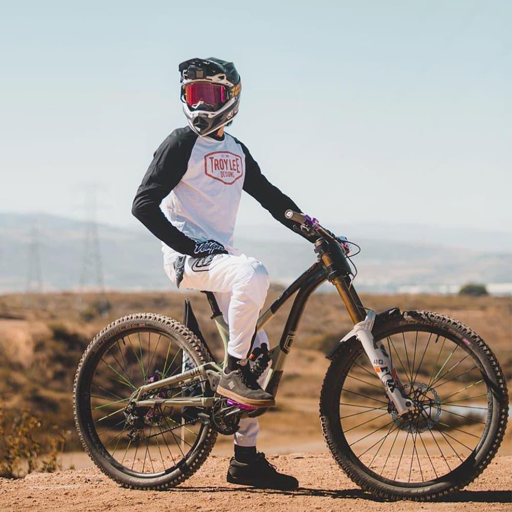 Mountain biker in full gear and helmet riding downhill bike on dirt trail outdoors