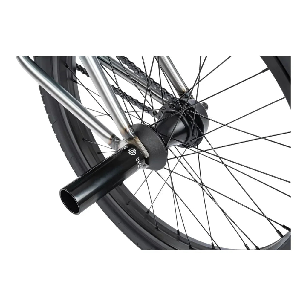 Détail de roue BMX avec moyeu noir et fourche chromée, chaîne et rayons visibles