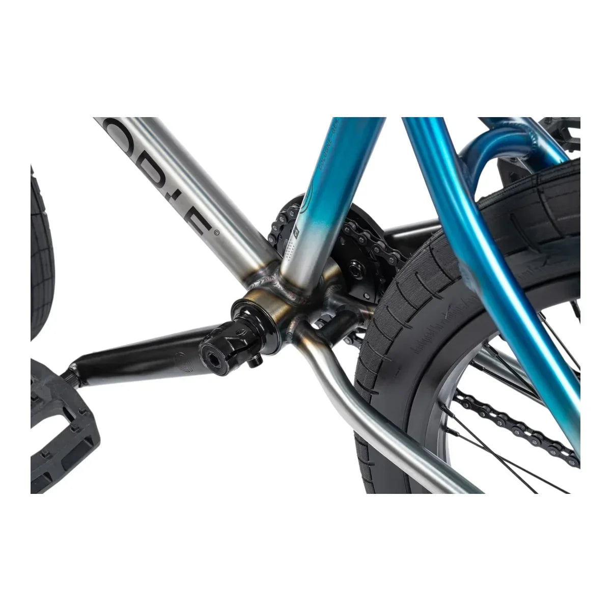 Détail cadre BMX bleu et argent avec pédalier et chaîne, roue arrière et pneu noir