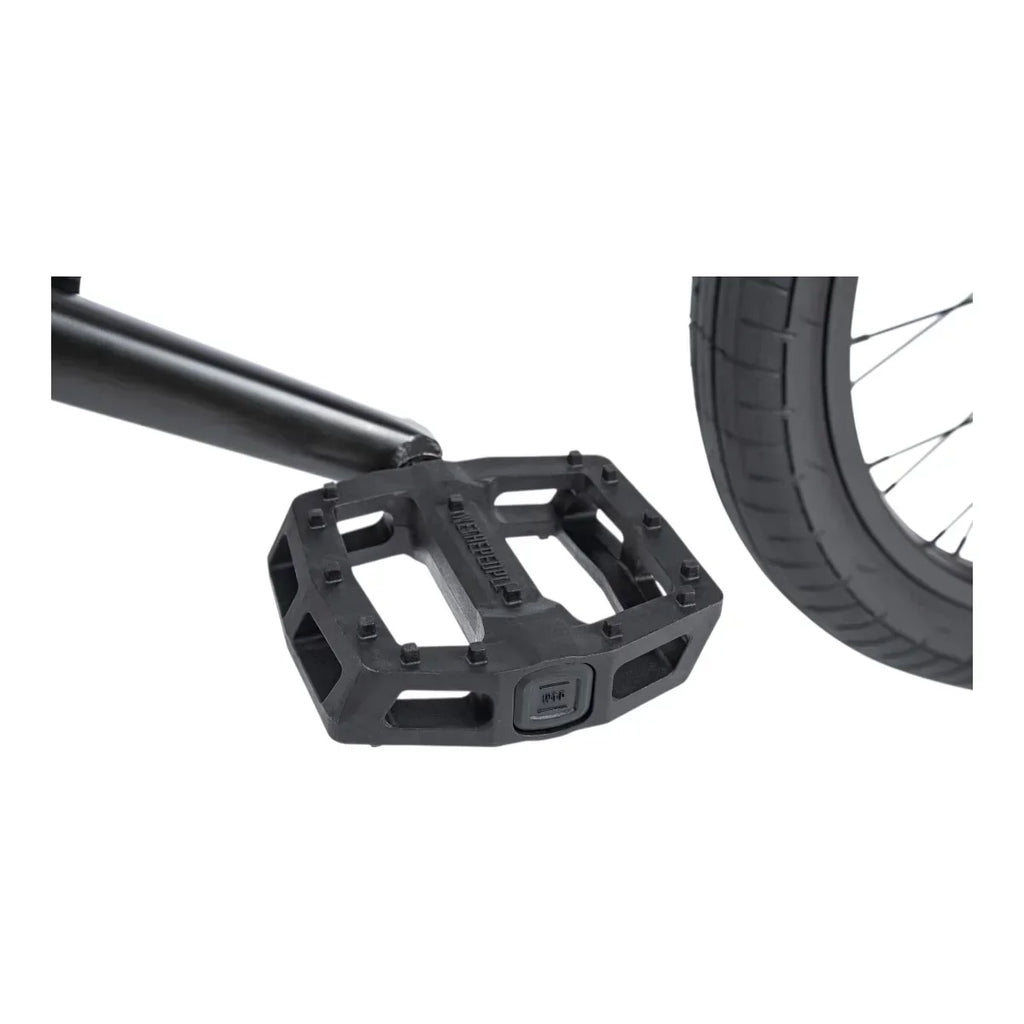 Pédale BMX noire robuste avec crampons et pneu de vélo en arrière-plan
