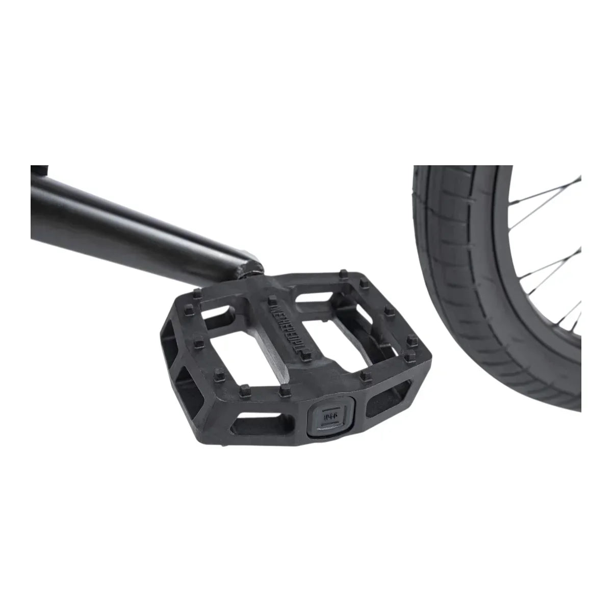 Pédale BMX noire robuste avec crampons et pneu de vélo en arrière-plan