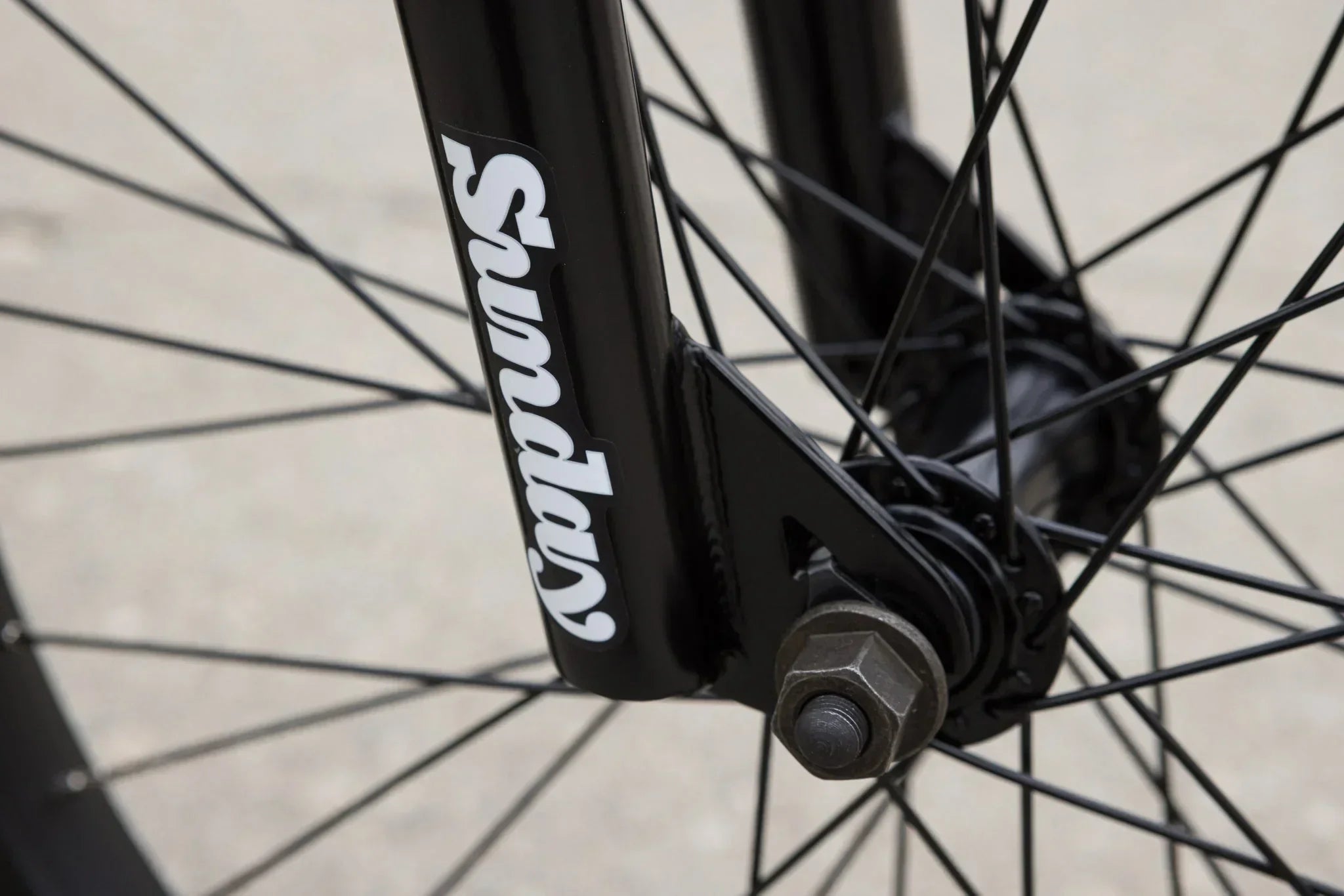 Gros plan de la fourche avant noire d'un vélo BMX avec le logo Sunday blanc.