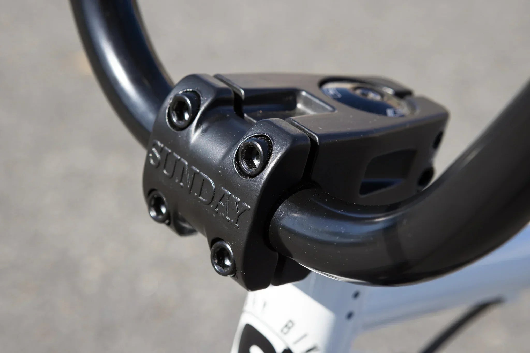 Gros plan d'une potence de vélo BMX noire de marque Sunday fixée au guidon