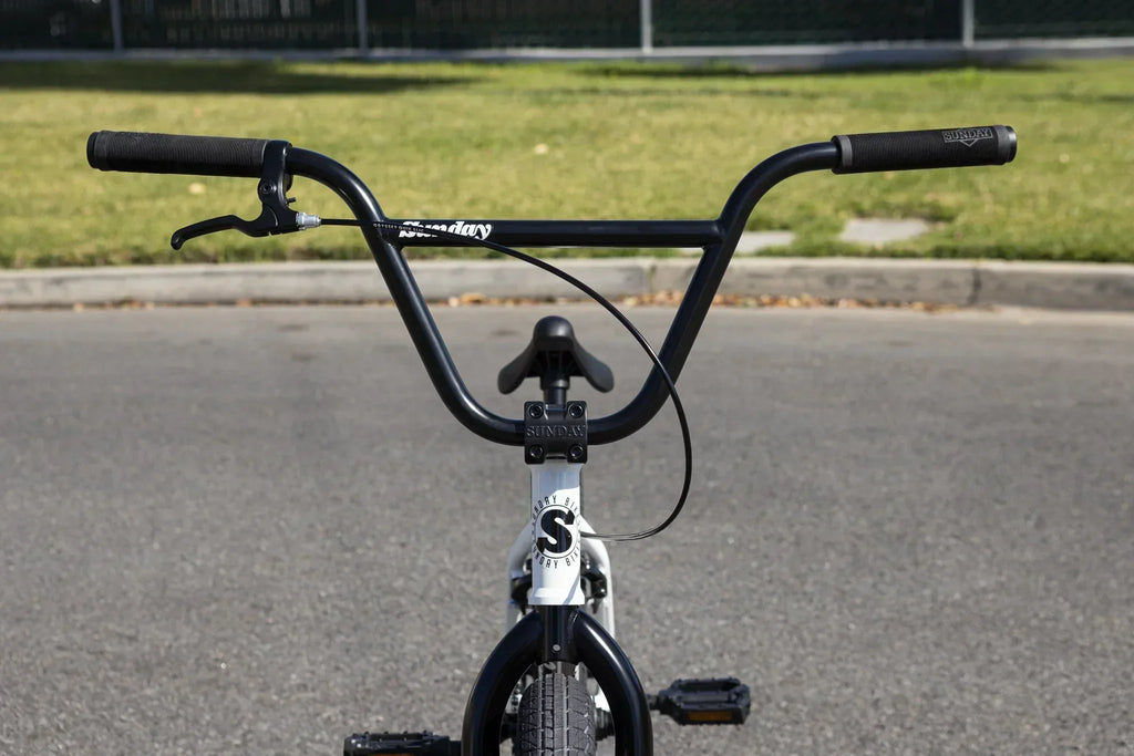 Vue arrière du guidon et de la selle d'un vélo BMX blanc Sunday sur le bitume.