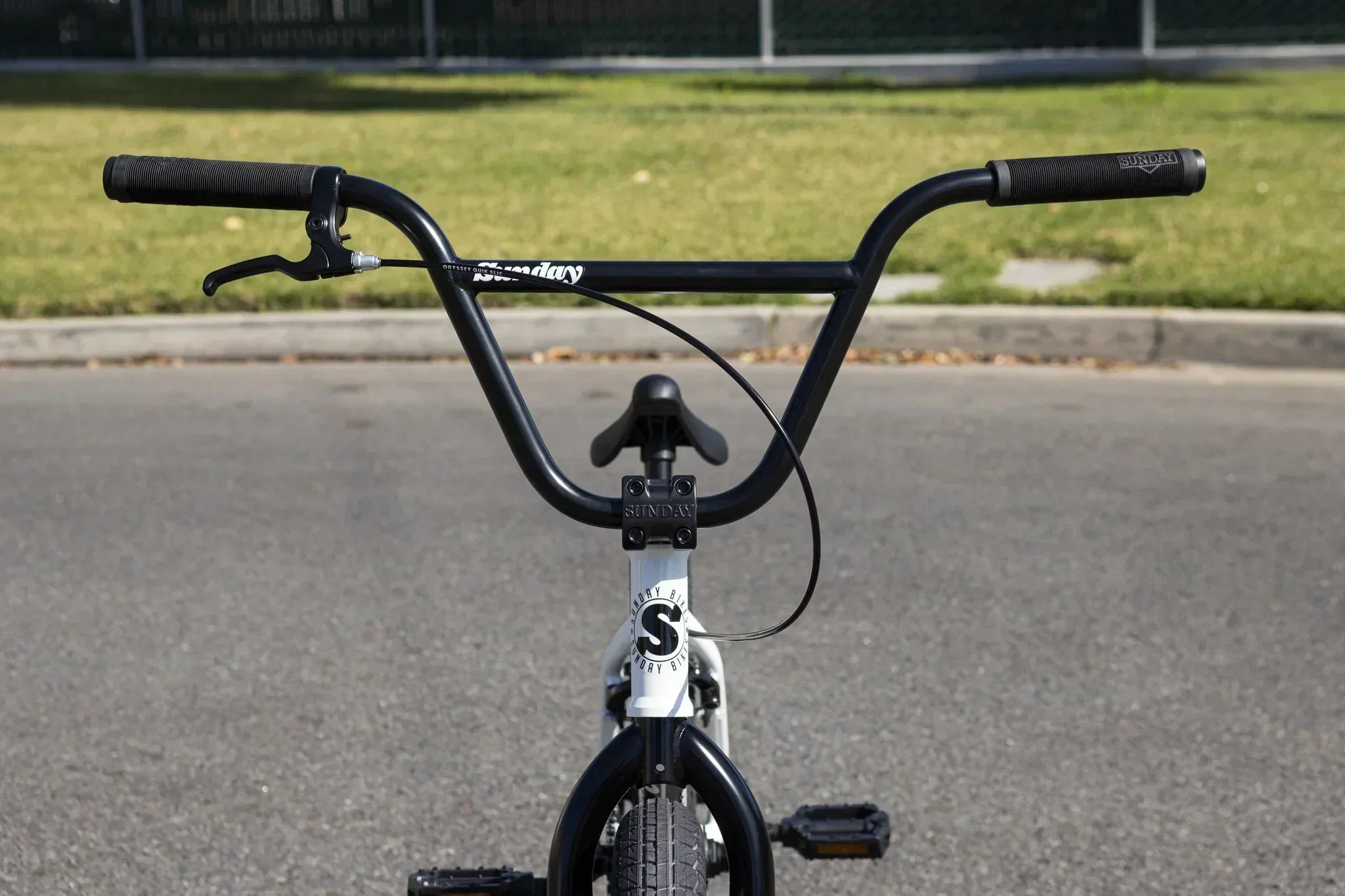 Vue arrière du guidon et de la selle d'un vélo BMX blanc Sunday sur le bitume.