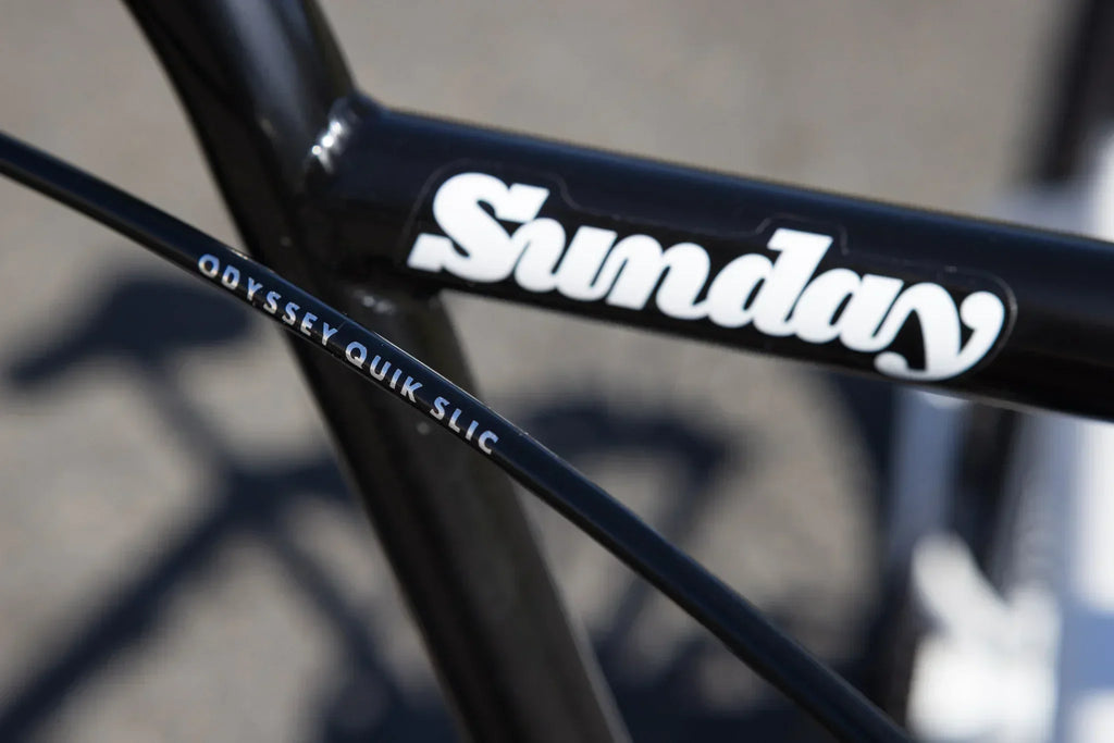 Gros plan d'un cadre de vélo BMX noir Sunday avec un câble Odyssey Quik Slic.
