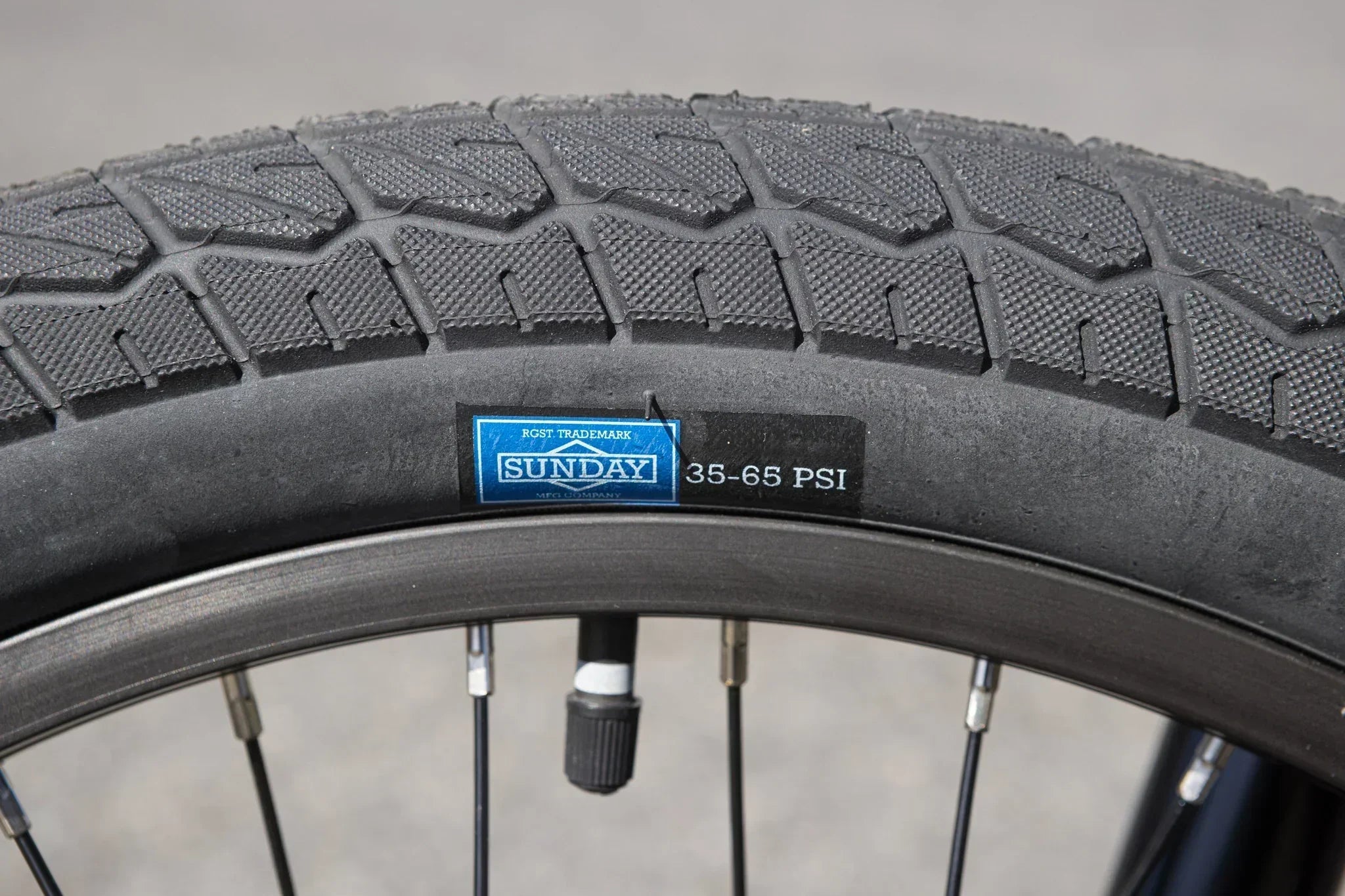 Gros plan d'un pneu de vélo BMX Sunday avec indication de pression 35-65 PSI.