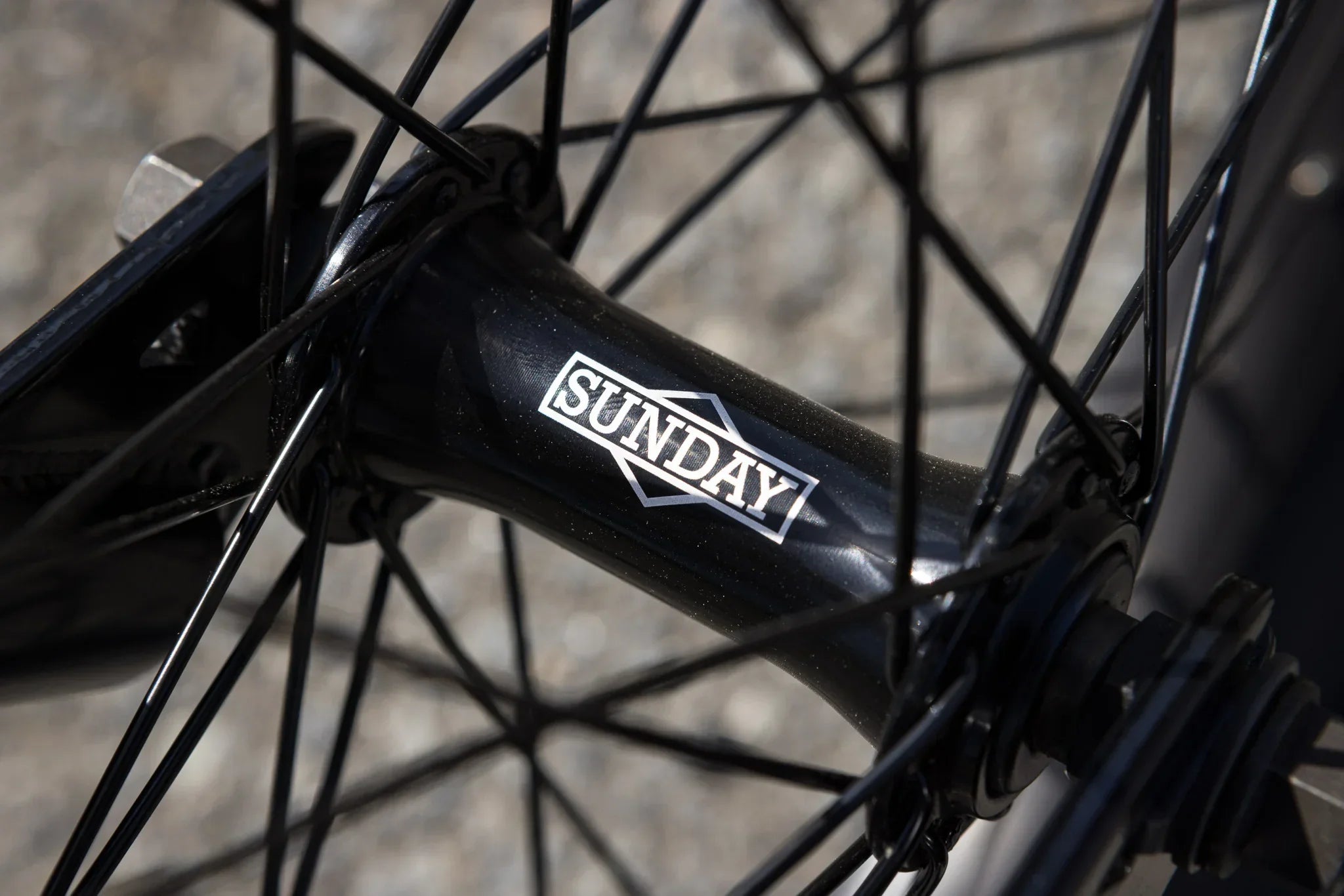 Gros plan du moyeu de roue BMX noir avec le logo Sunday blanc