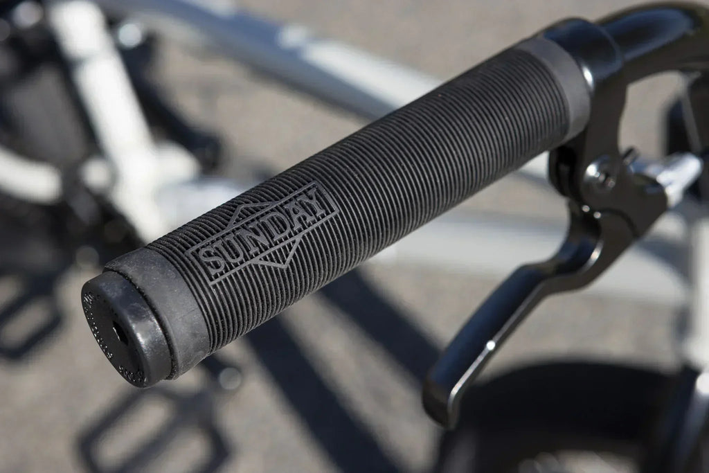 Gros plan d'une poignée de guidon BMX noire texturée de marque Sunday avec levier de frein.