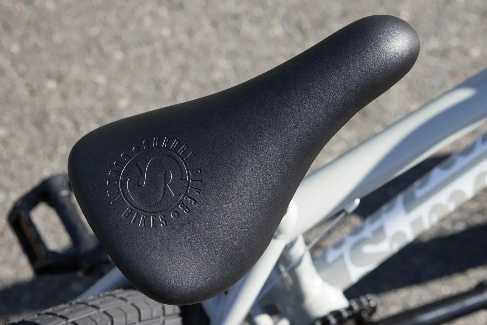Selle de vélo BMX noire avec logo Sunday Bikes embossé sur cadre blanc