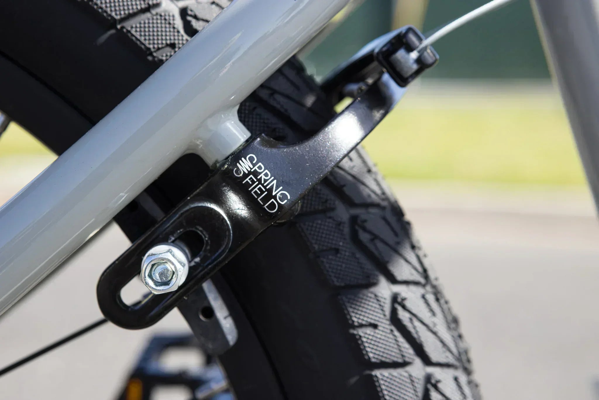 Gros plan d'un frein Spring Field noir monté sur un vélo BMX gris