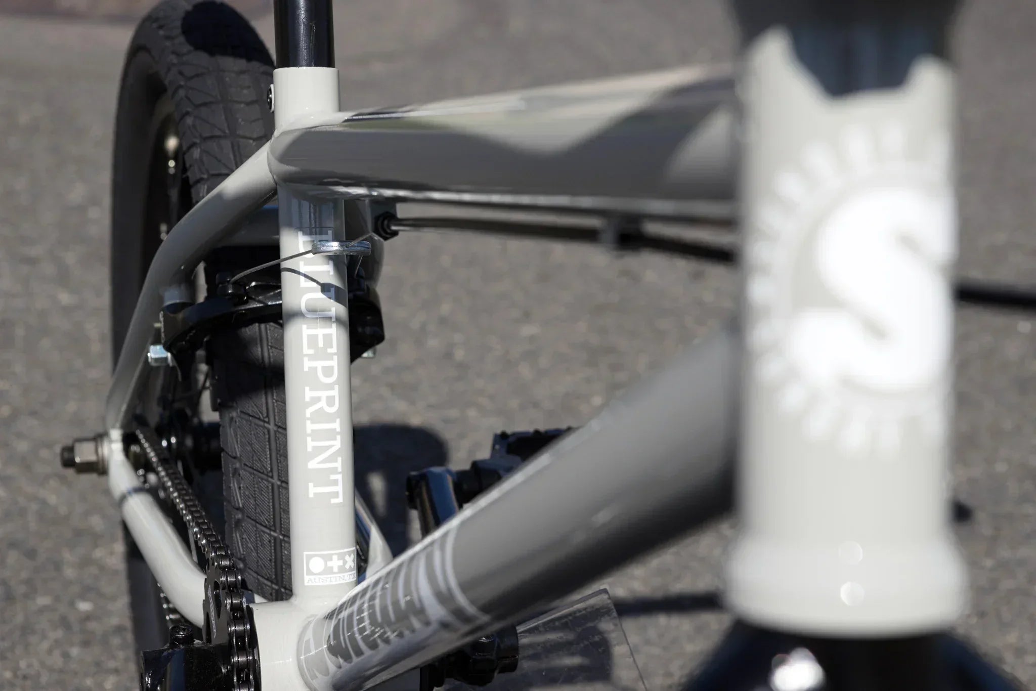 Gros plan du cadre gris d'un vélo BMX Blueprint avec détails du tube et de la chaîne.