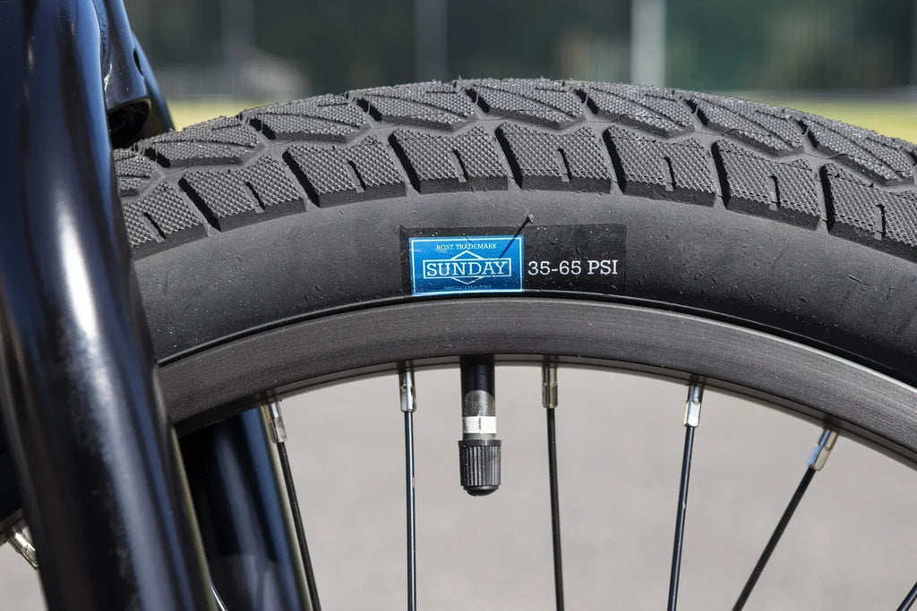 Gros plan d'un pneu de vélo BMX Sunday avec indication de pression 35-65 PSI.