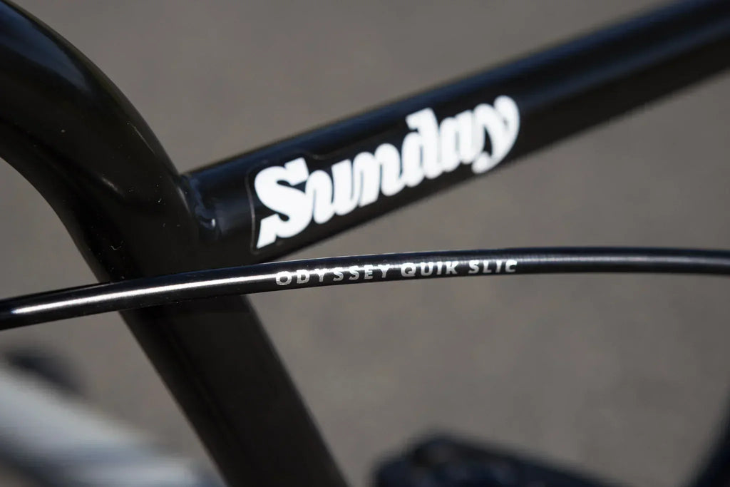 Gros plan du cadre noir de vélo BMX Sunday avec câble Odyssey Quik Slic.