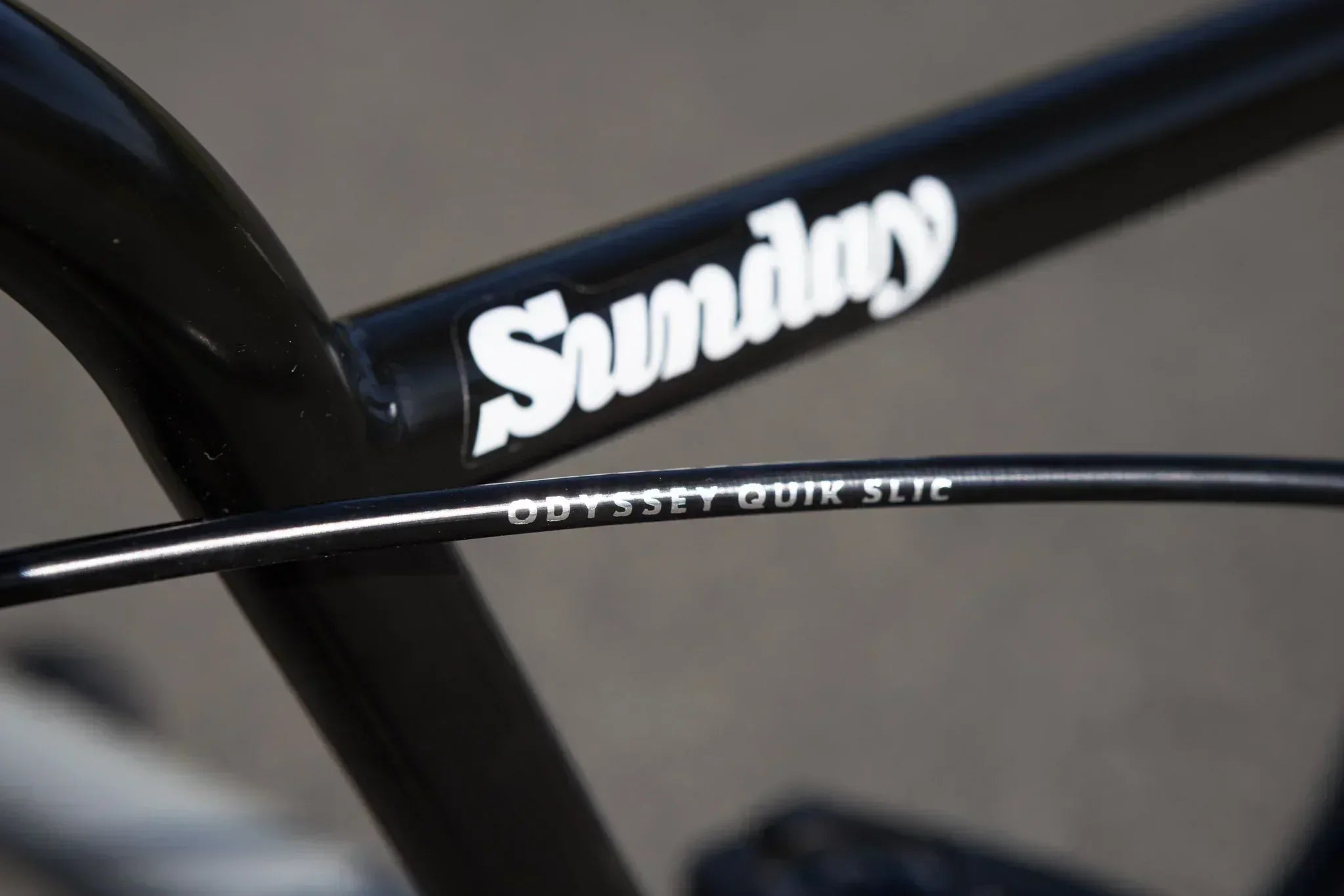 Gros plan du cadre noir de vélo BMX Sunday avec câble Odyssey Quik Slic.