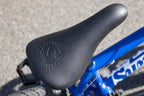 Gros plan d'une selle de vélo BMX noire sur un cadre bleu vif.