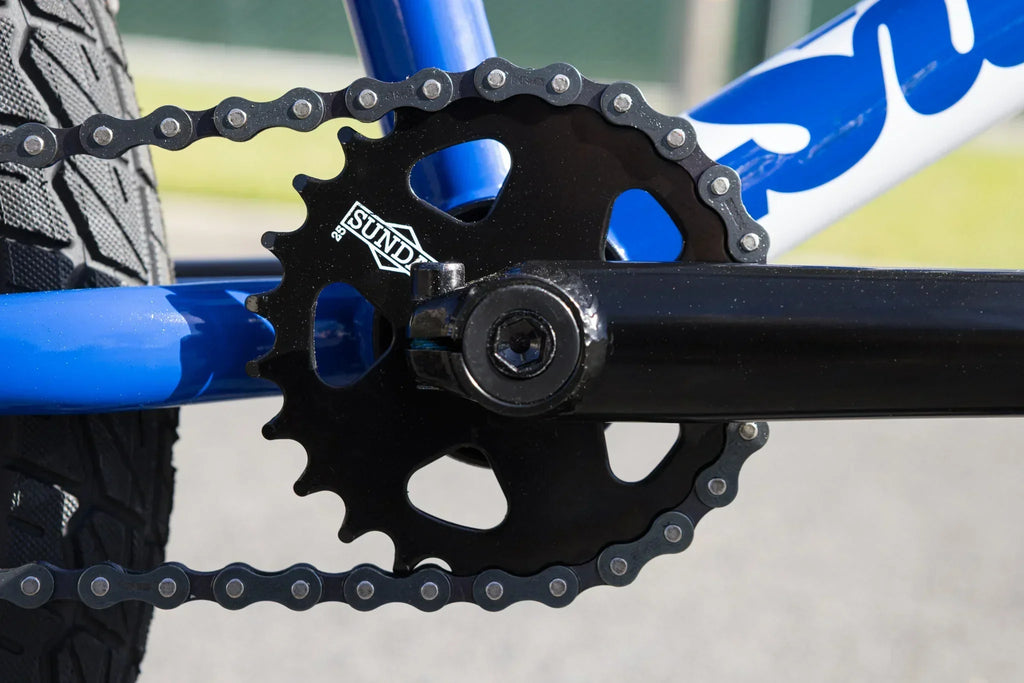Gros plan d'un plateau de pédalier Sundae noir sur un cadre de vélo BMX bleu.
