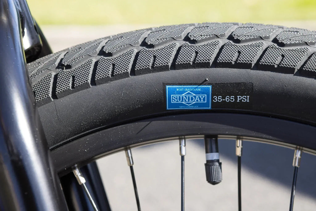 Gros plan d'un pneu de vélo BMX Sunday avec indication de pression 35-65 PSI.