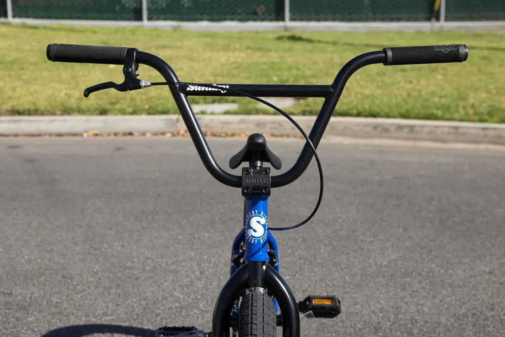 Vue rapprochée du guidon noir et du cadre bleu d'un vélo BMX Sunday