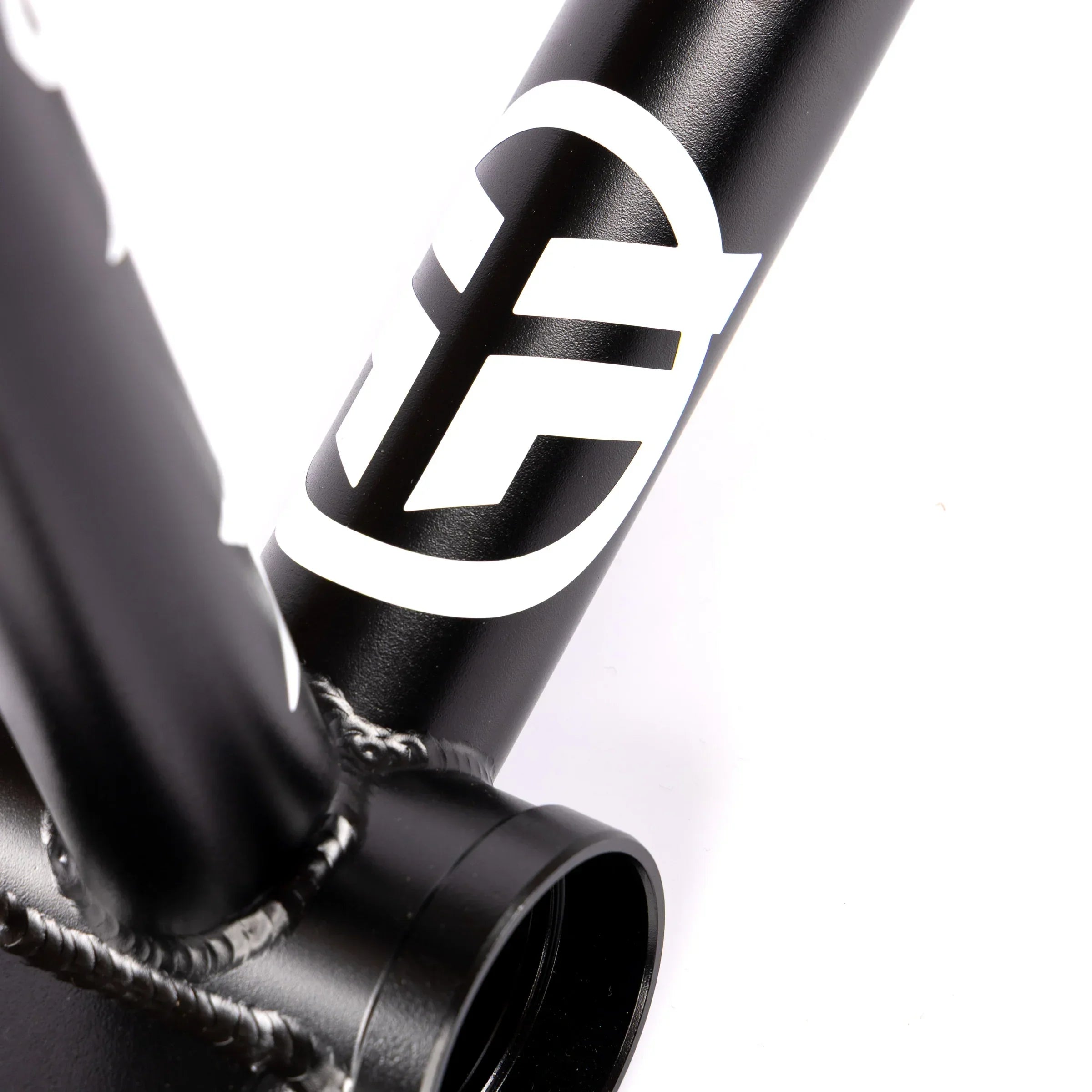 Close-up of matte black BMX bike frame with white logo and visible welds