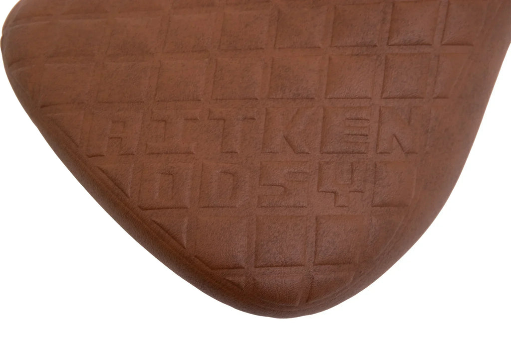 Selle BMX marron avec motif quadrillé et logo gravé, design ergonomique pour vélo freestyle