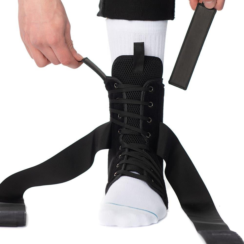 Person adjusting black lace-up ankle support brace over white sock
