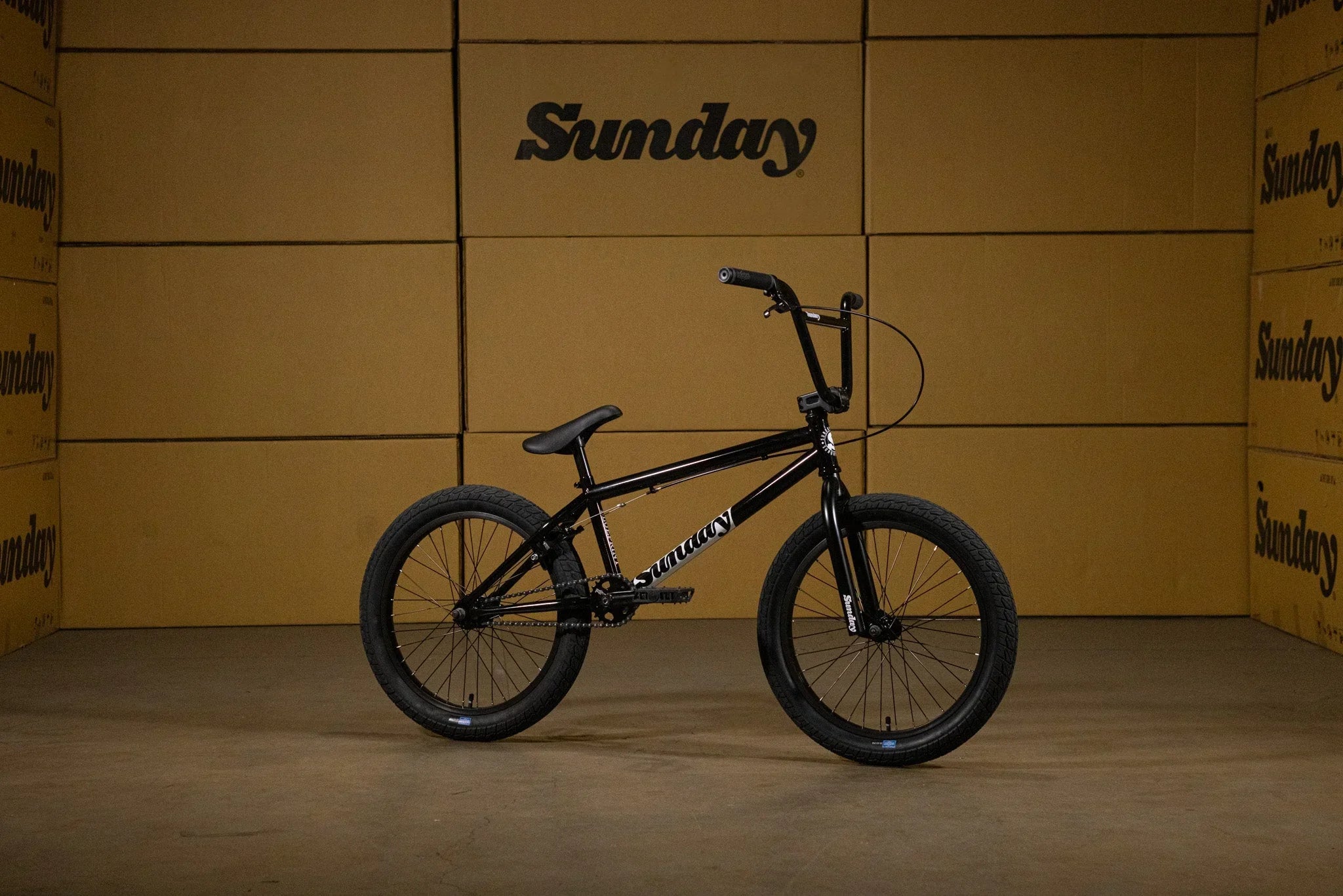 Vélo BMX Sunday noir sur fond de cartons de marque Sunday
