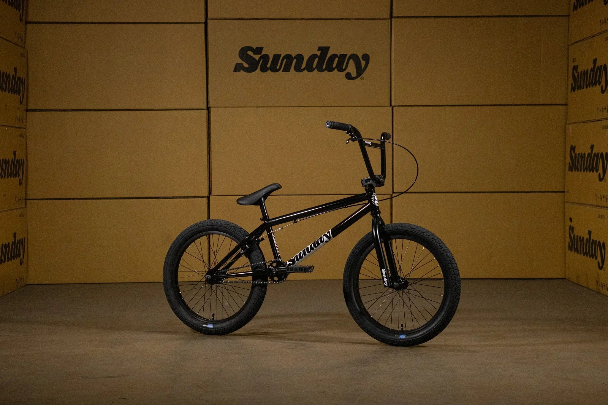 Vélo BMX Sunday noir sur fond de cartons de marque Sunday