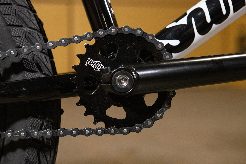 Gros plan du plateau et de la chaîne d'un vélo BMX noir de marque Sund