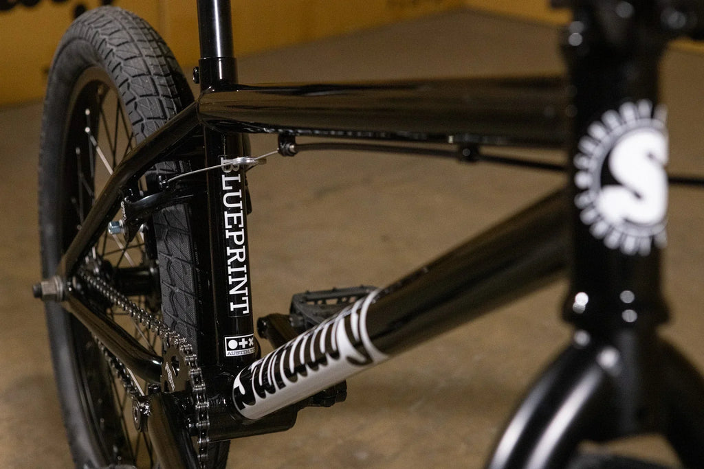 Détail du cadre noir d'un vélo BMX Blueprint avec pneus tout-terrain.