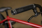 Gros plan d'une poignée de guidon BMX noire avec logo Sunday sur un vélo rouge