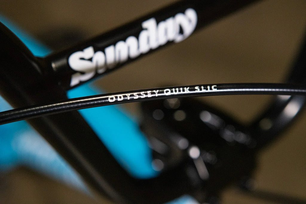 Gros plan d'un câble de frein Odyssey Quik Slic sur un cadre de vélo BMX Sunday noir.