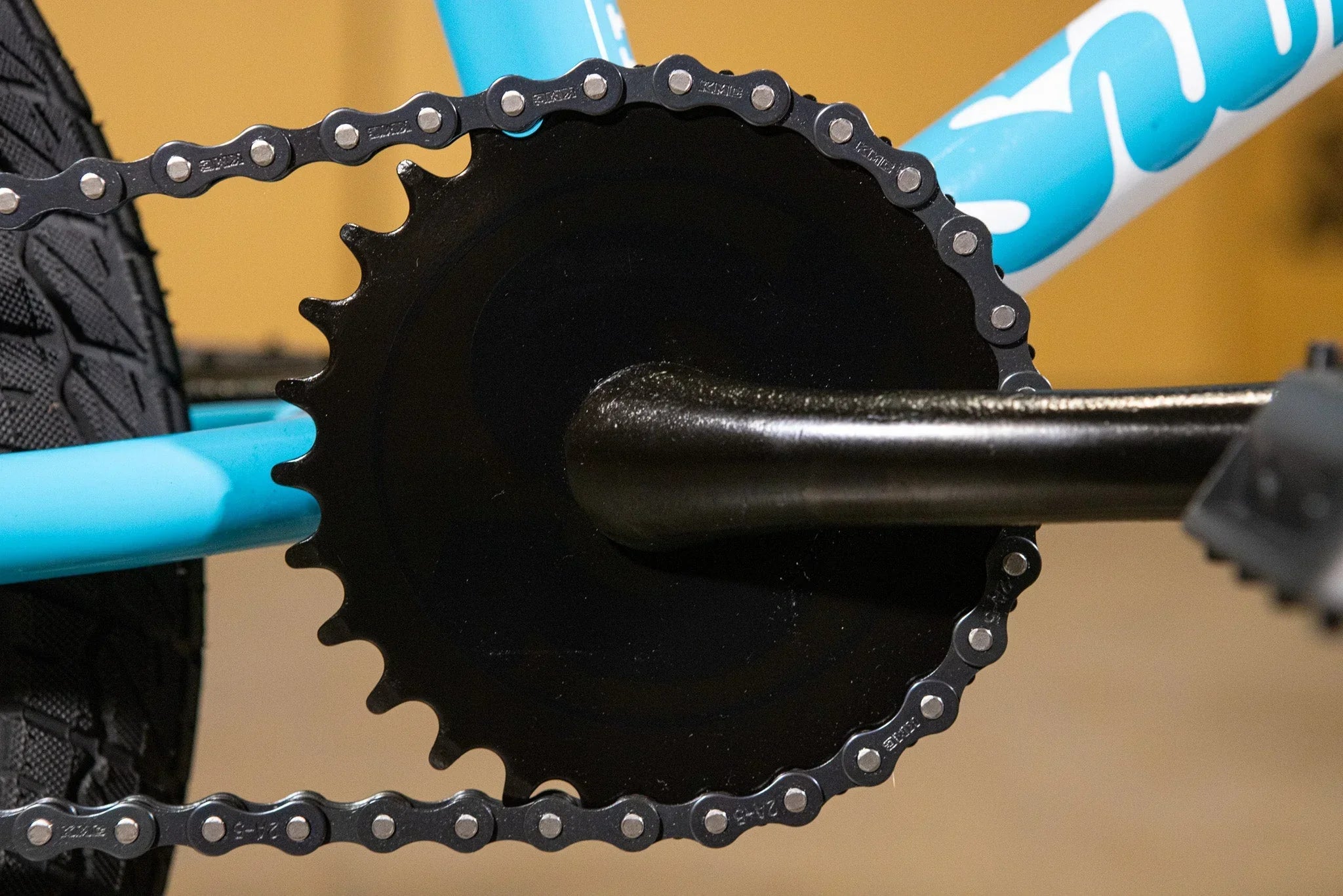 Gros plan d'un plateau noir et d'une chaîne de vélo BMX sur un cadre bleu.