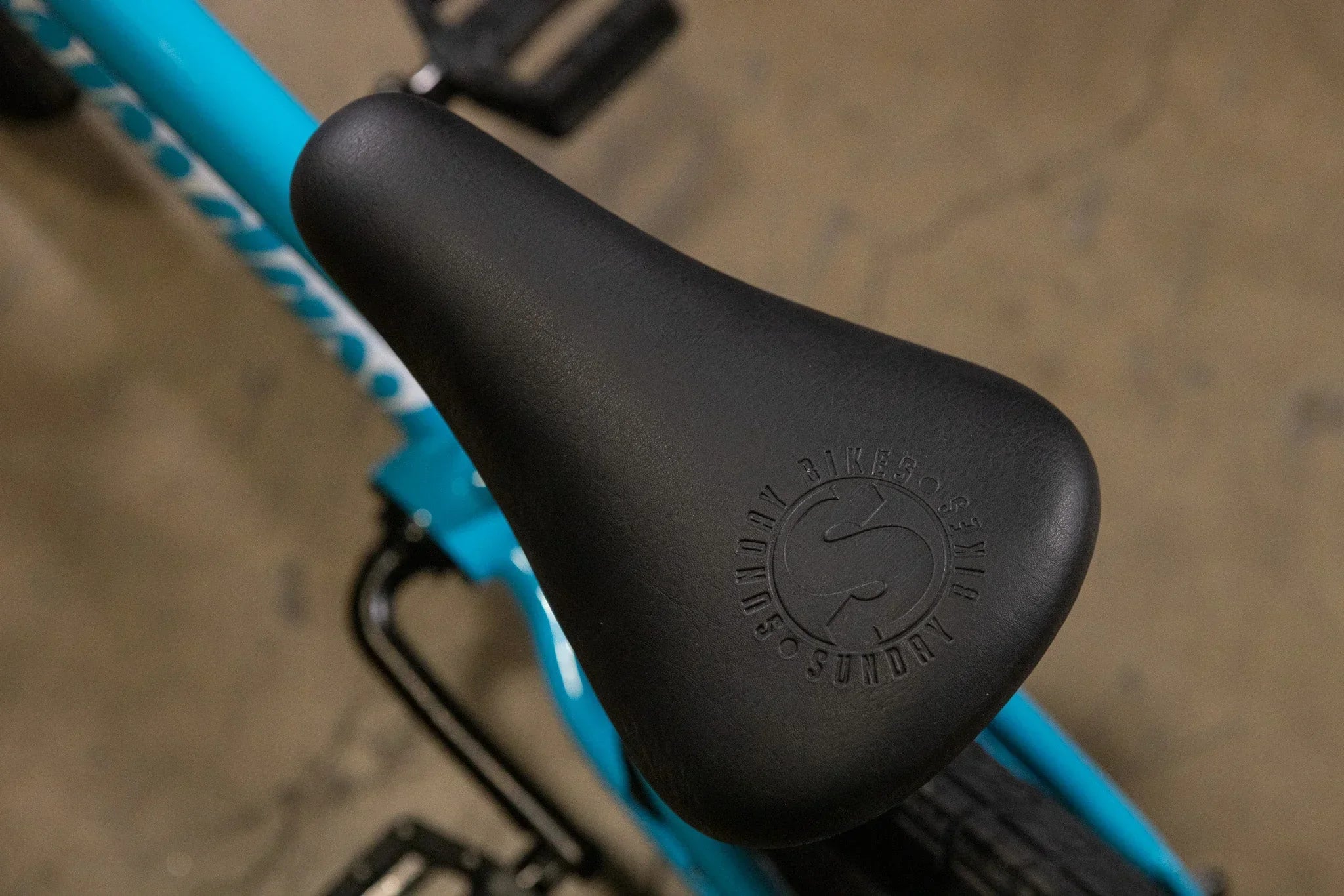 Gros plan d'une selle de vélo BMX noire avec logo Sunday sur un cadre bleu