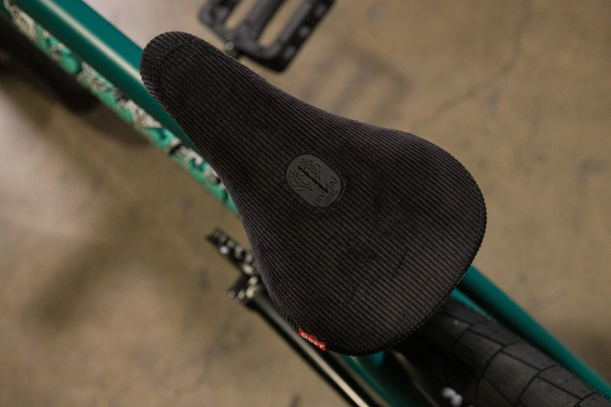Selle de BMX noir texturé avec logo circulaire sur un vélo de couleur vert émeraude