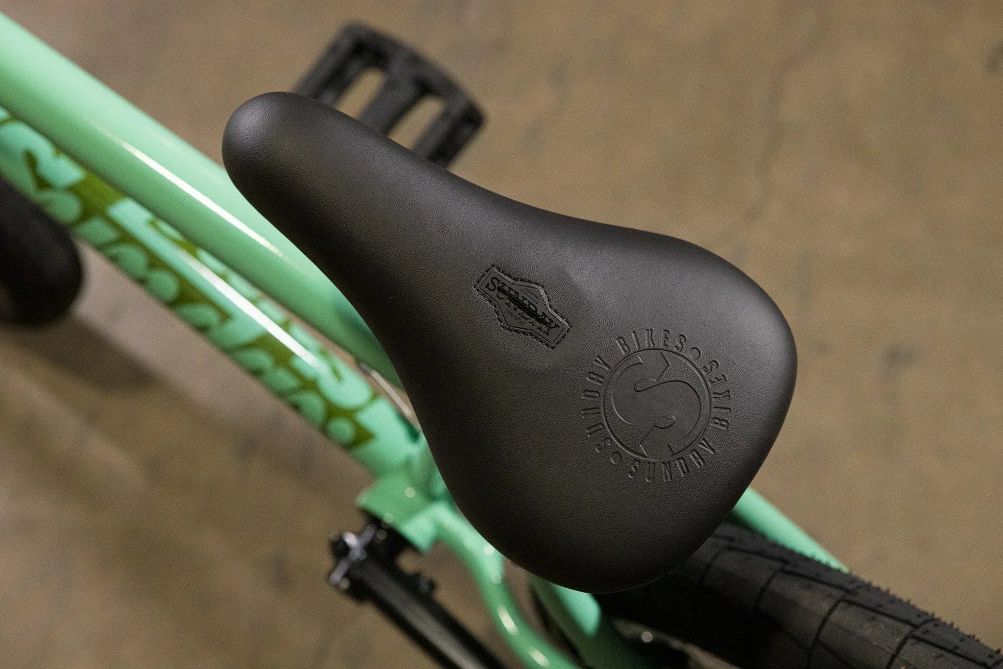Gros plan d'une selle de vélo BMX noire Sundy sur un cadre vert menthe.