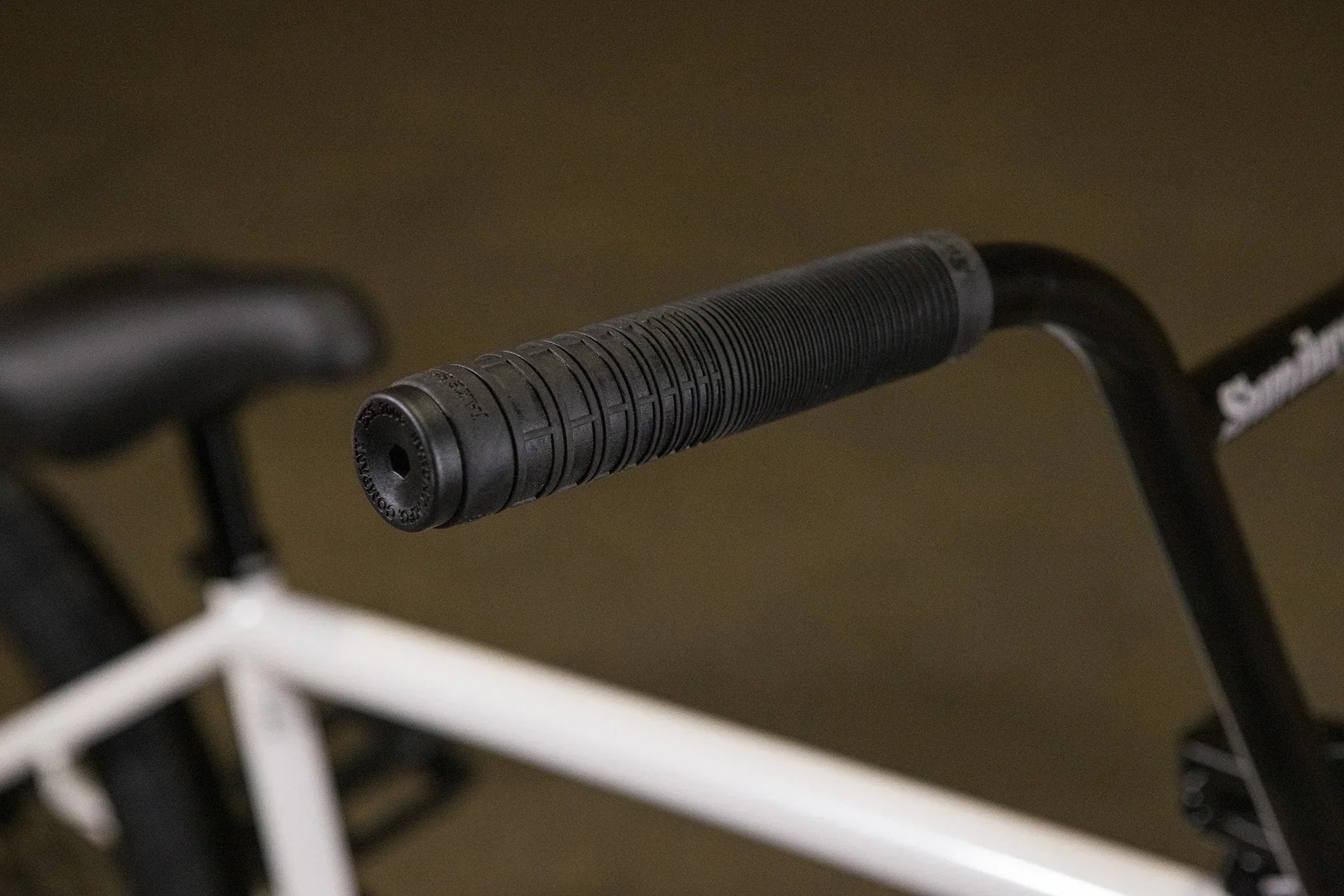 Gros plan d'une poignée de guidon noire texturée sur un vélo BMX blanc