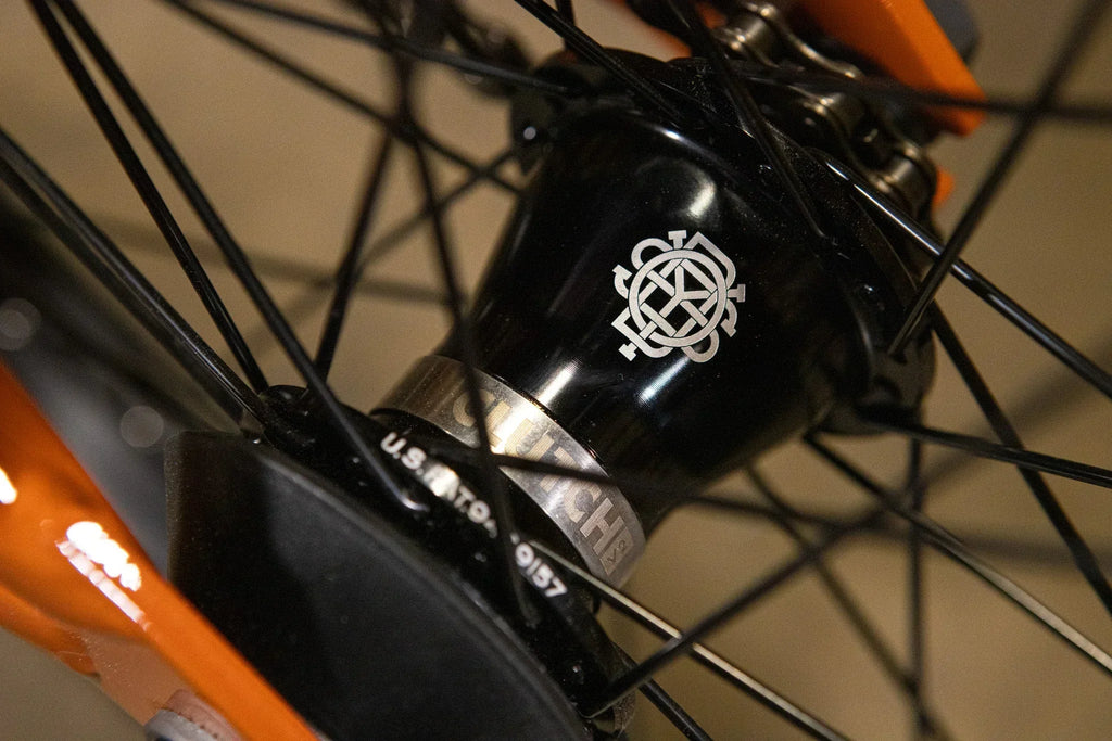 Gros plan sur le moyeu noir d'une roue de BMX avec un logo blanc gravé.