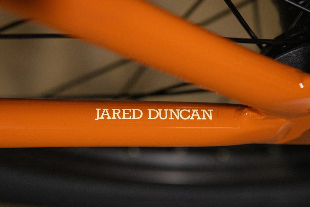 Gros plan du cadre orange d'un vélo BMX avec l'autocollant Jared Duncan.