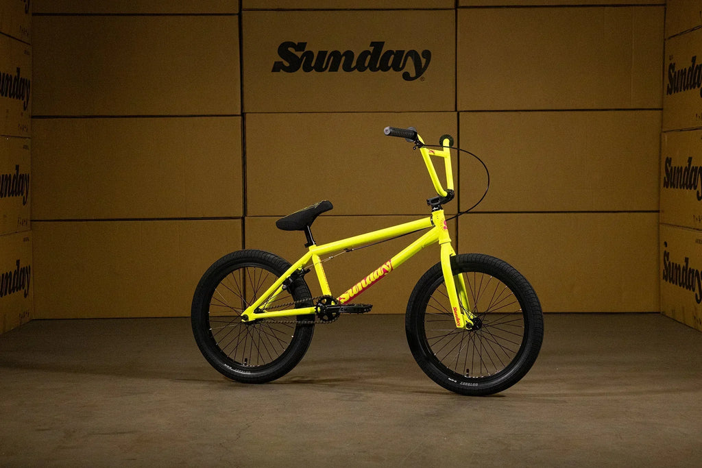 Vélo BMX jaune vif Sunday posé devant des cartons bruns.