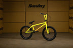 Vélo BMX jaune vif Sunday posé devant des cartons bruns.
