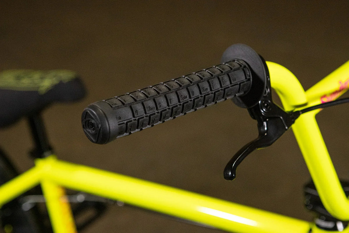 Gros plan d'une poignée de guidon noire sur un cadre de vélo BMX jaune vif