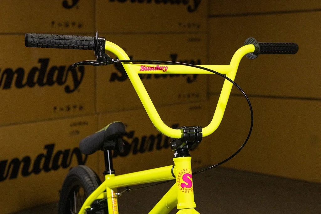 Gros plan du guidon jaune fluo d'un vélo BMX Sunday avec poignées noires