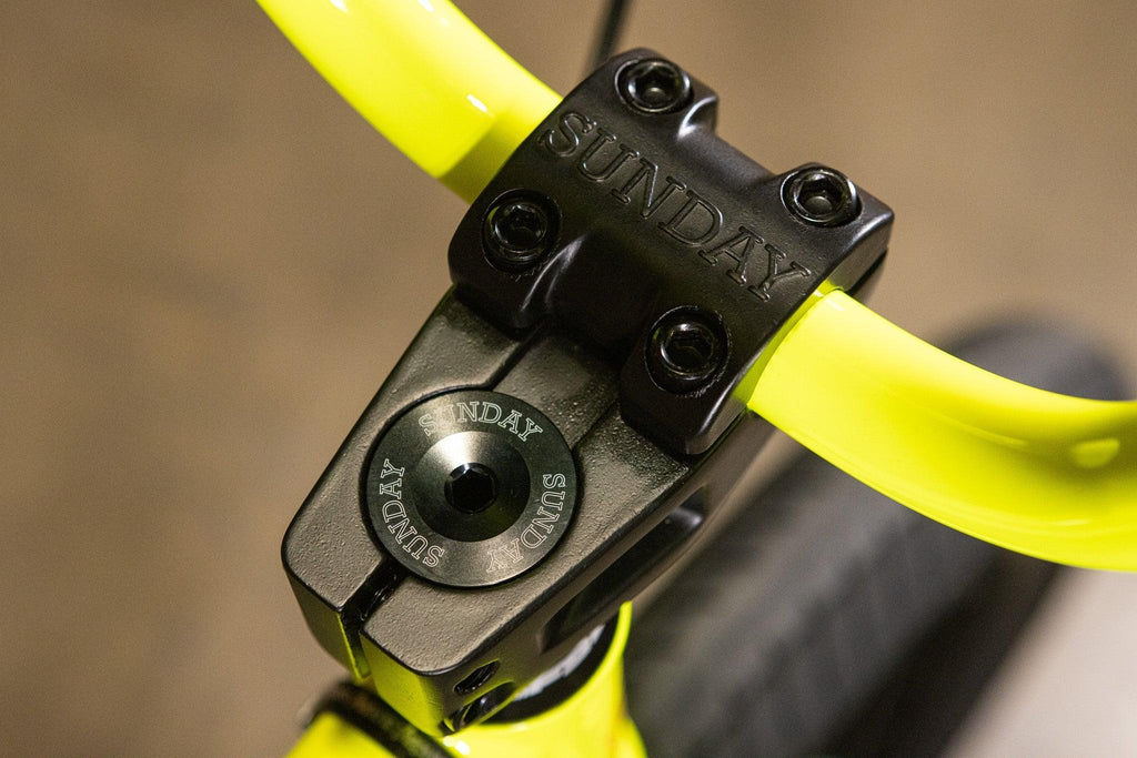 Pot de guidon BMX noir Sunday fixé sur un guidon jaune fluo