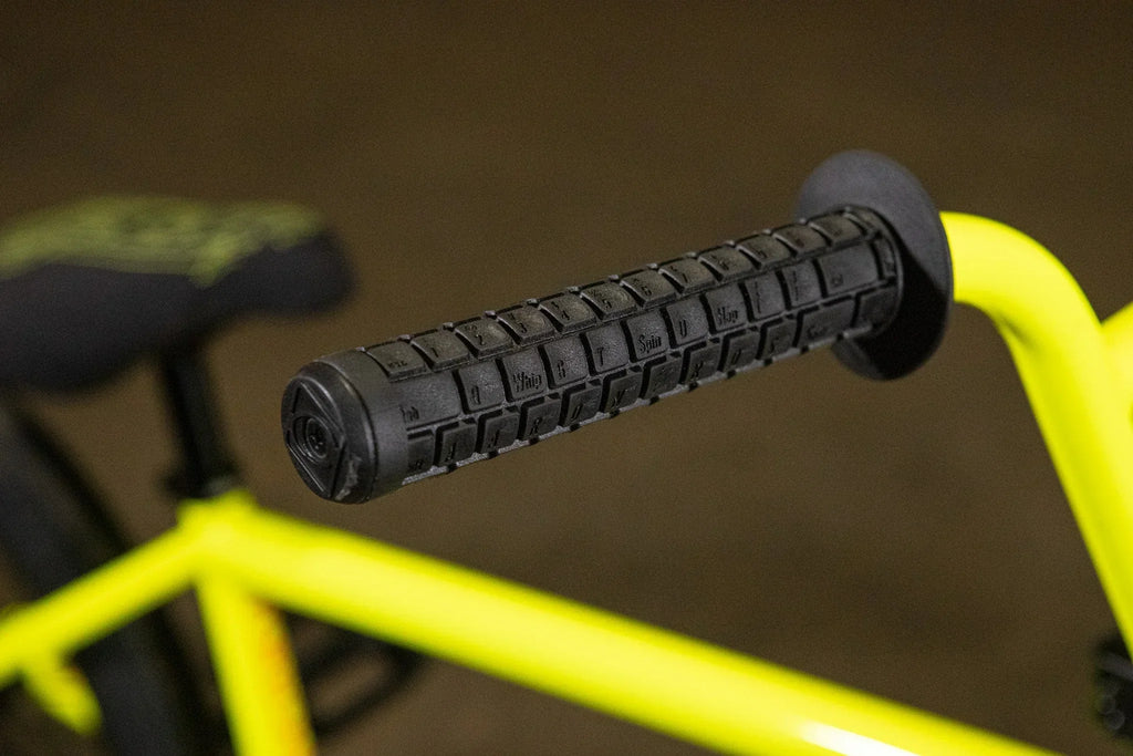 Gros plan d'une poignée de guidon noire texturée sur un cadre de BMX jaune fluo.