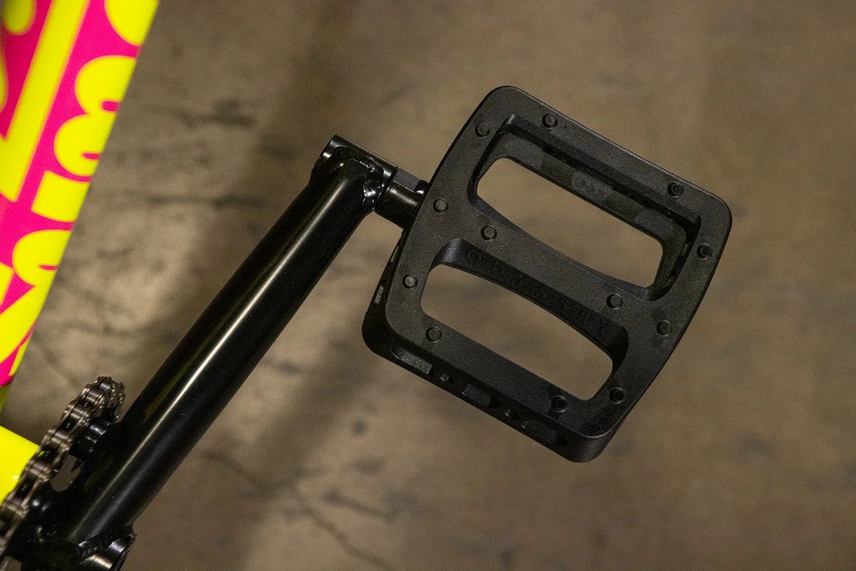 Gros plan d'une pédale de BMX noire avec picots sur une manivelle noire