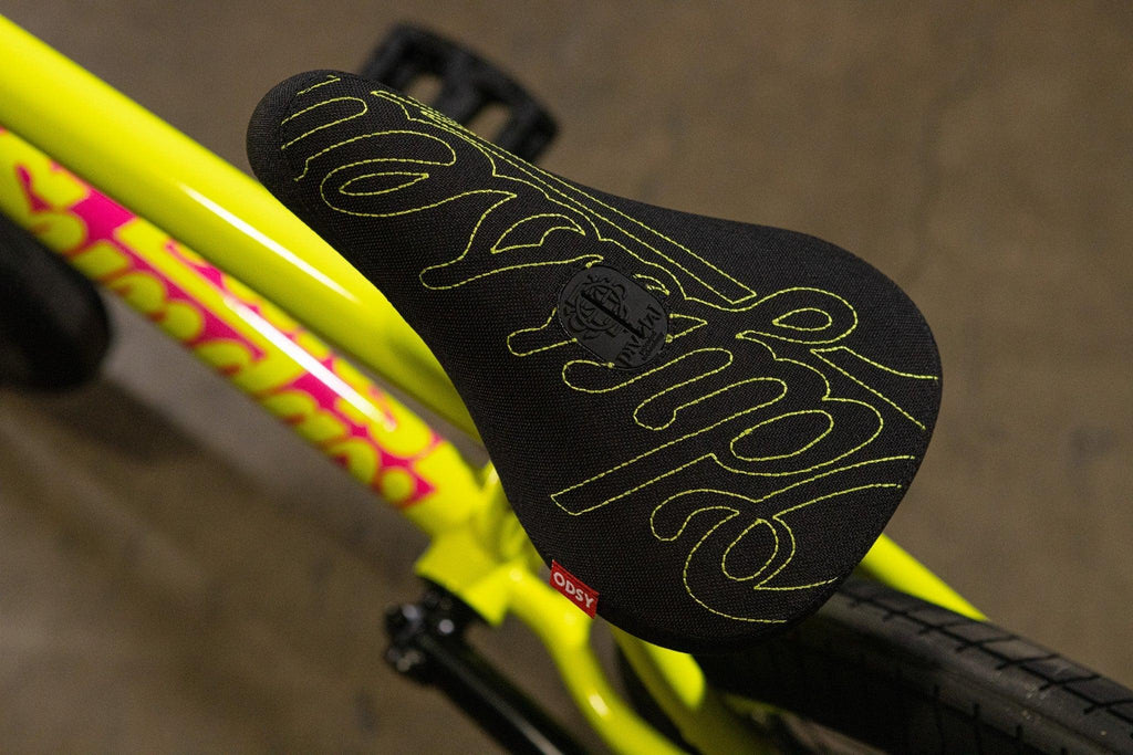 Selle de vélo BMX noire avec lettrage jaune et logo Odysy sur cadre jaune vif