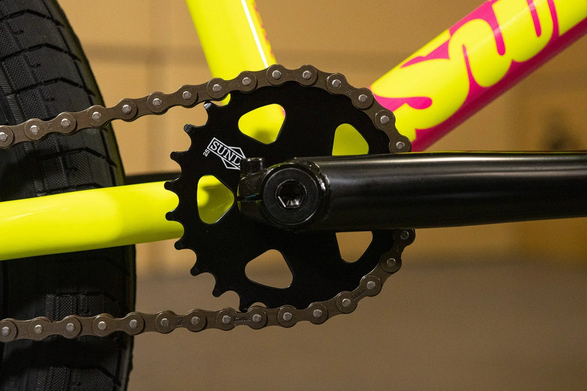 Gros plan du plateau SUNL noir et de la chaîne sur un cadre de vélo BMX jaune fluo.