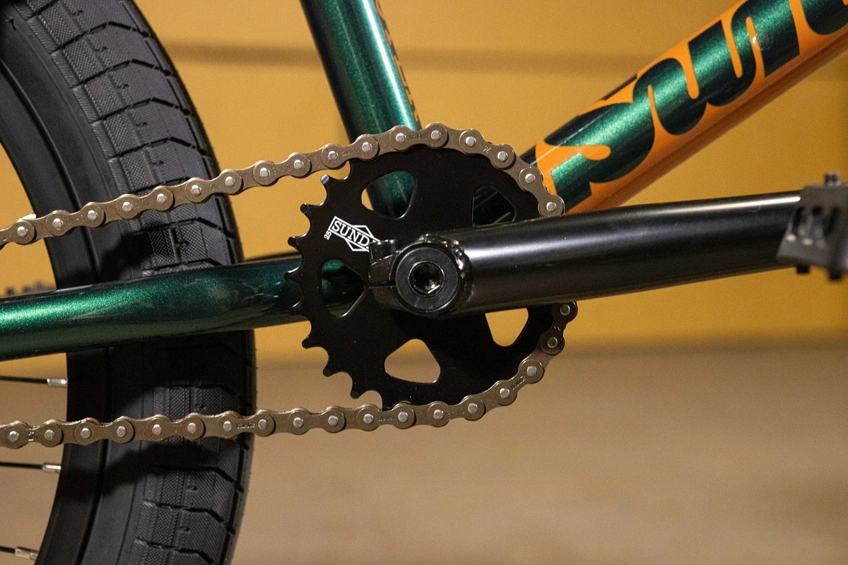 Détail du plateau et de la chaîne d'un vélo BMX vert métallisé