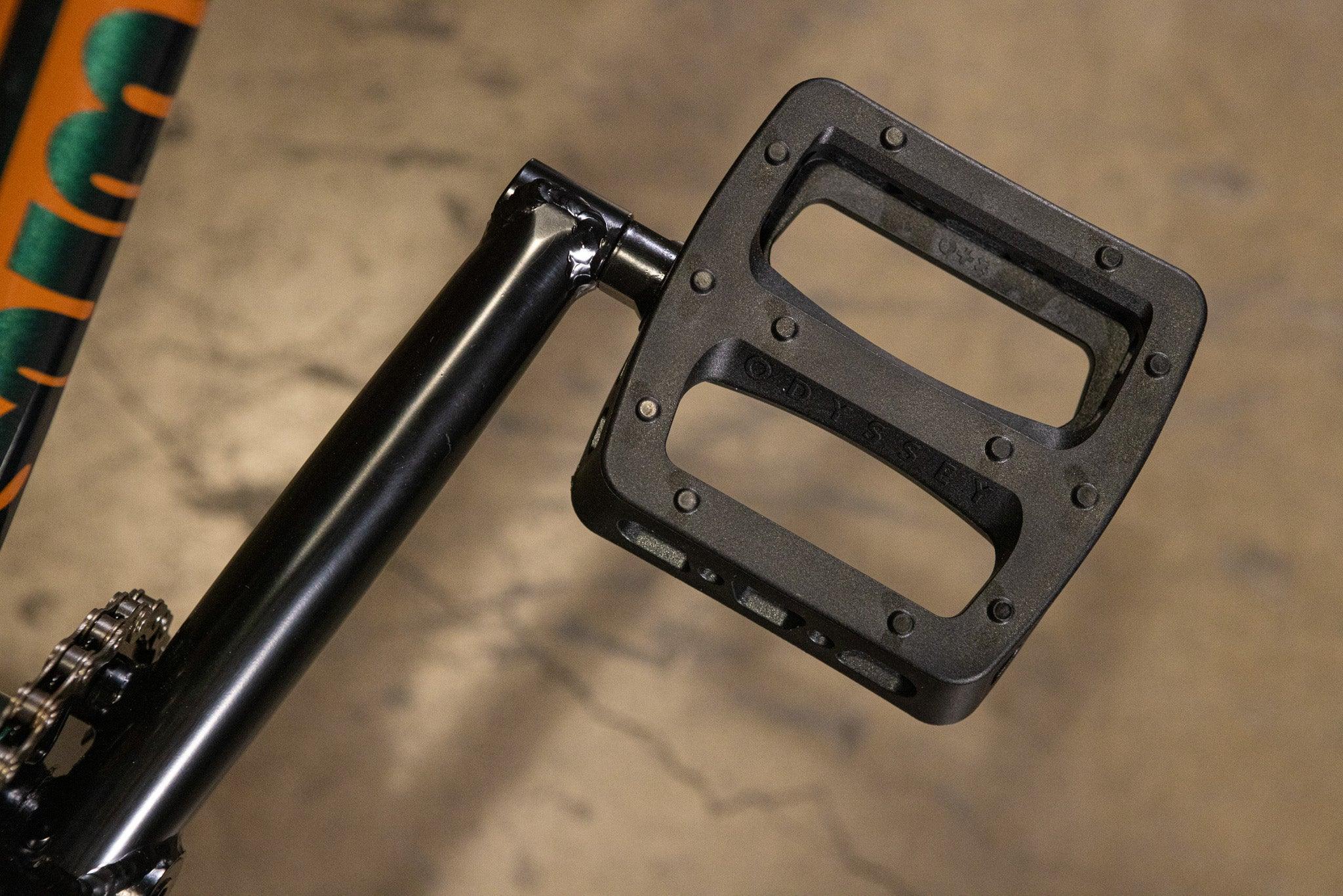 Gros plan d'une pédale Odyssey noire sur un vélo BMX